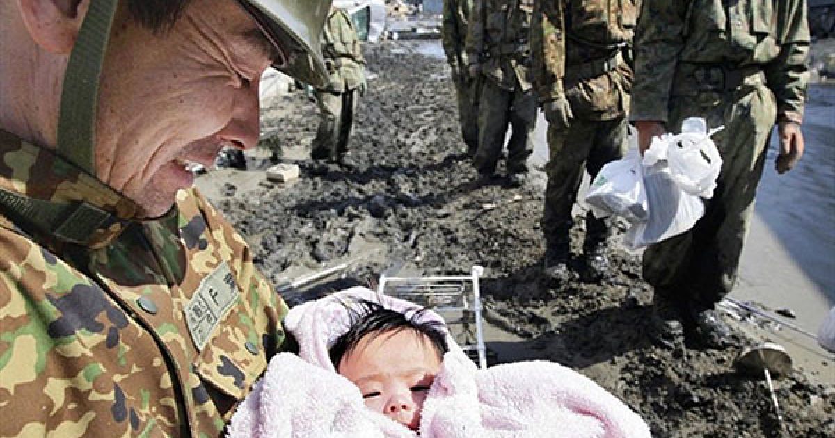 Японія, Ісіномакі. Солдат самооборони тримає на руках чотиримісячну дитину, яка вижила після руйнівного цунамі у місті Ісіномакі, префектура Міягі. Кількість жертв руйнівного землетрусу та цунамі в Японії перевищило 10 тисяч осіб. / © AFP