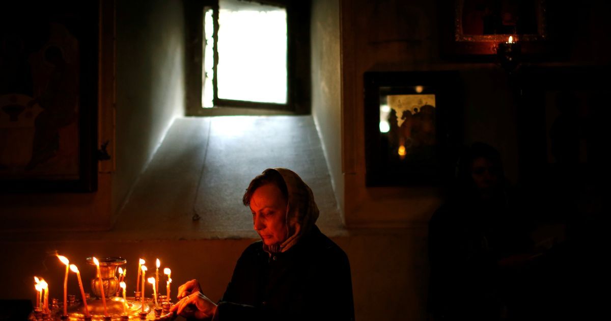 Женщина зажигает свечу в Тбилиси, Грузия / © Reuters