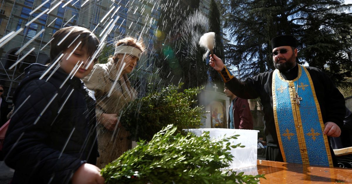 Священник благословляет верующих святой водой в Тбилиси, Грузия / © Reuters