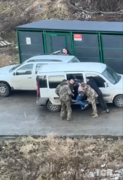 Троє людей у військовій формі досить грубо заштовхували чоловіка до білого буса