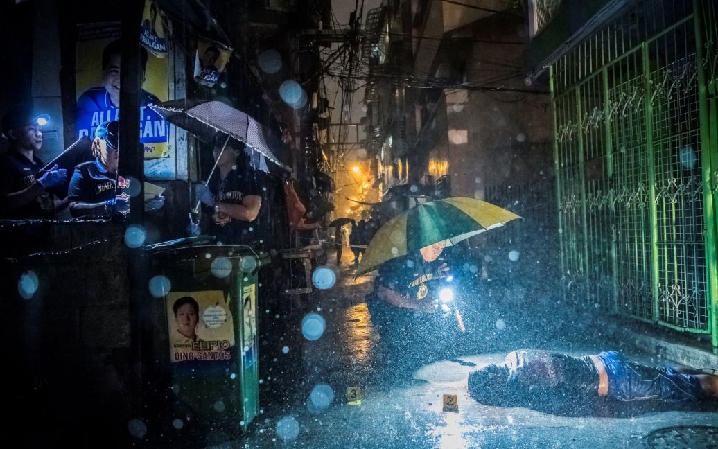 Серия фотографий Дэниеля Береулака получила приз в категории &laquo;Новости&raquo;. На фотографии: полиция собирает показания на месте, где Ромео Джоэл Торрес был убит двумя вооруженными людьми на мотоциклах рано утром в Маниле. / © Reuters
