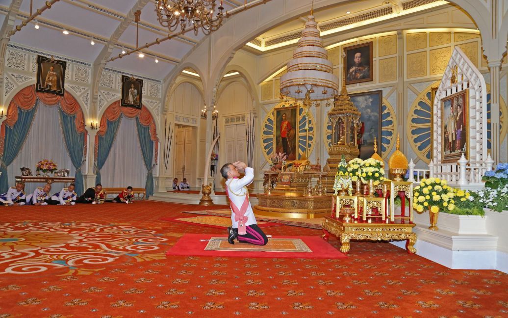 Новий король Таїланду Маха Вачіралонгкорн стоїть навколішки перед портретом покійного короля Пхумілона Адальядета і королеви Сірікіт під час його коронації у палаці Дусіт в Бангкоку, Таїланд. / © Reuters