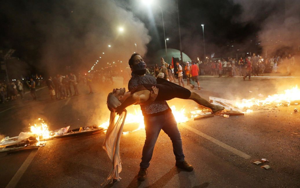 Антиправительственные демонстранты выступают перед горящей баррикадой, протестуя против конституционной поправки, известной как PEC 55, которая ограничивает государственные расходы, перед Национальным конгрессом Бразилии в Бразилиа, Бразилия. / © Reuters