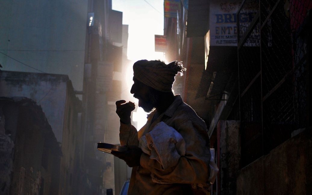 Безпритульний їсть свій сніданок на вулиці у Бангалорі, Індія. / © Reuters