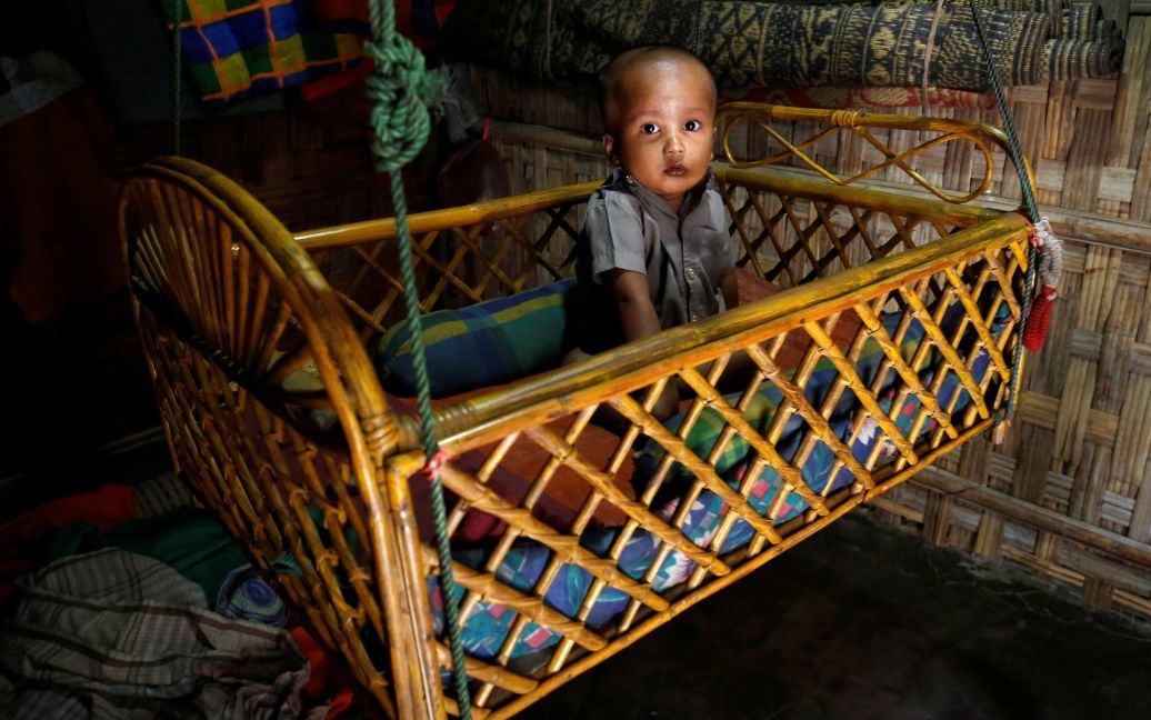 Дитина реагує на камеру, сидячи у колисці у незареєстрованому таборі біженців у Кокс Базар, Бангладеш. / © Reuters