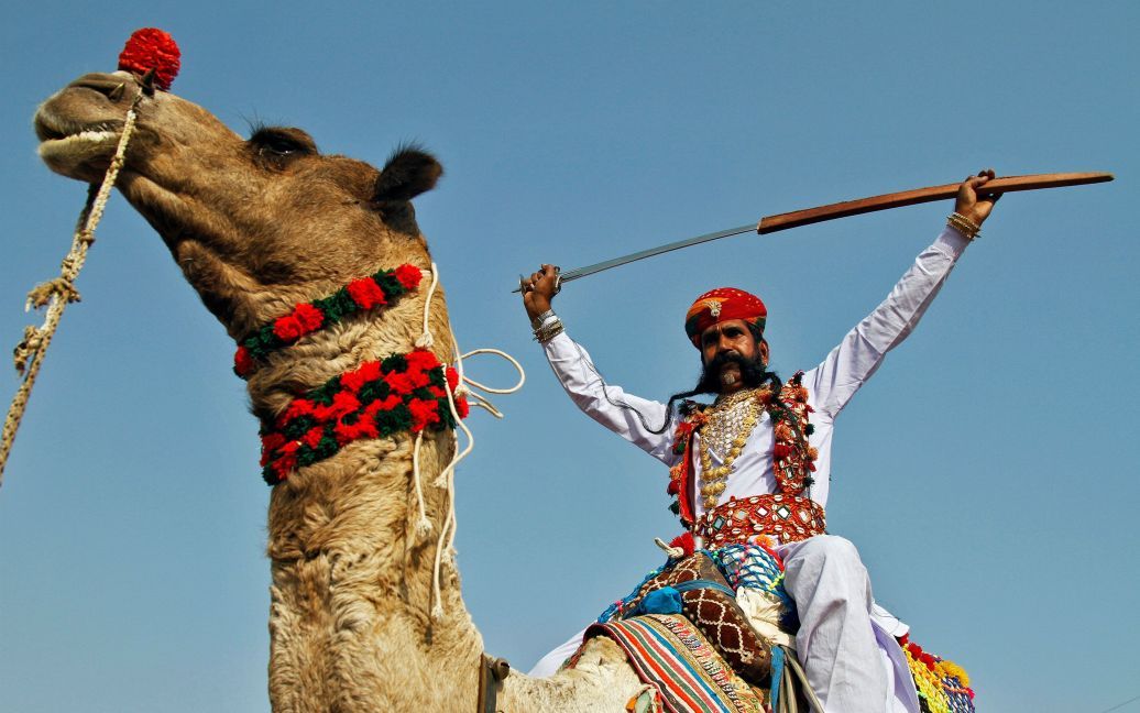 Артист поднимает меч на последний день Пушкарь, в ходе которого тысячи животных, в основном верблюдов, приносят на ярмарку, чтобы продать, в штате Раджастан, Индия. / © Reuters