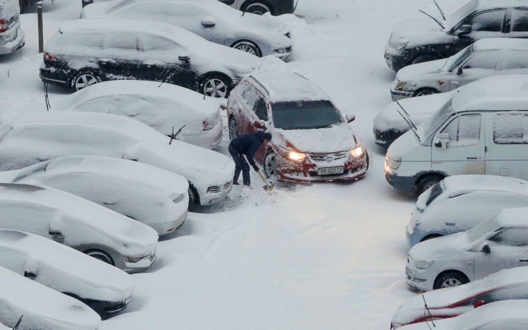 Человек убирает снег на парковке в Киеве. / © Reuters