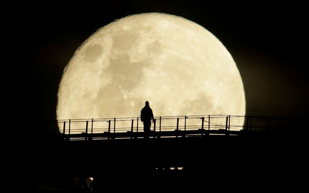 Человек идет на верхнем пролете Sydney Harbour Bridge, в то время как Суперлуние вступает в завершающую фазу в Сиднее, Австралия. / © Reuters