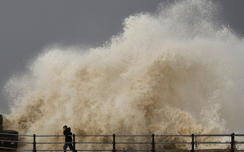 Женщина убегает от большой волны на набережной в Нью-Брайтоне, Северная Англия. / © Reuters