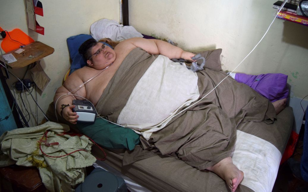 32-летний мексиканец Хуан Педро лежит в своей кровати у себя дома, дожидаясь фельдшеров, которые должны доставить его в больницу в Гвадалахаре, где он должен пройти курс лечения для того, чтобы сбросить лишний от его 500-килограммового веса. / © Reuters