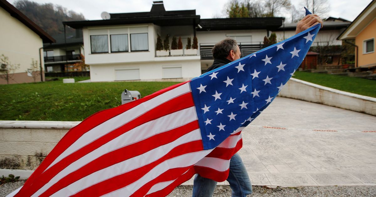 Чоловік з американським прапором перед домом батьків Меланії Трамп у Севніца