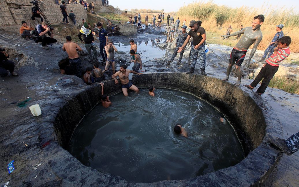 Місцеві мешканці і бійці іракської армії купаються у ставку у місті Хаммам аль-Алі, на південь від Мосула, Ірак. / © Reuters