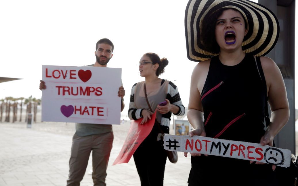 Демонстранты держат плакаты во время акции протеста против избрания Дональда Трампа президентом Соединенных Штатов перед зданием посольства США в Тель-Авиве, Израиль. / © Reuters