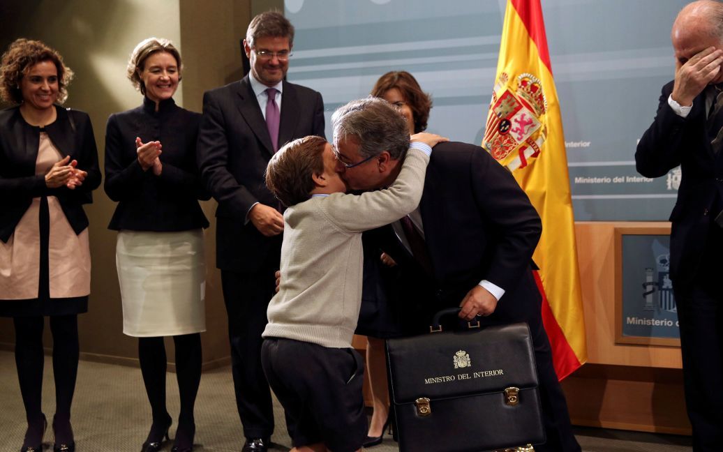 Син цілує нового міністра внутрішніх справ Іспанії Хуана Ігнасіо Зойдо після того, як він отримав портфель міністра від свого попередника. / © Reuters