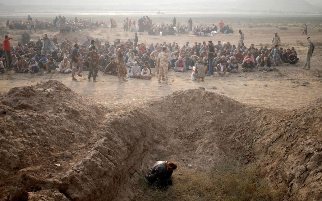 Підозрюваний у причетності до &ldquo;Ісламської держави&rdquo; сидить в яру неподалік переміщених людей біля КПП в Кайара на схід від Мосула, Ірак. / © Reuters