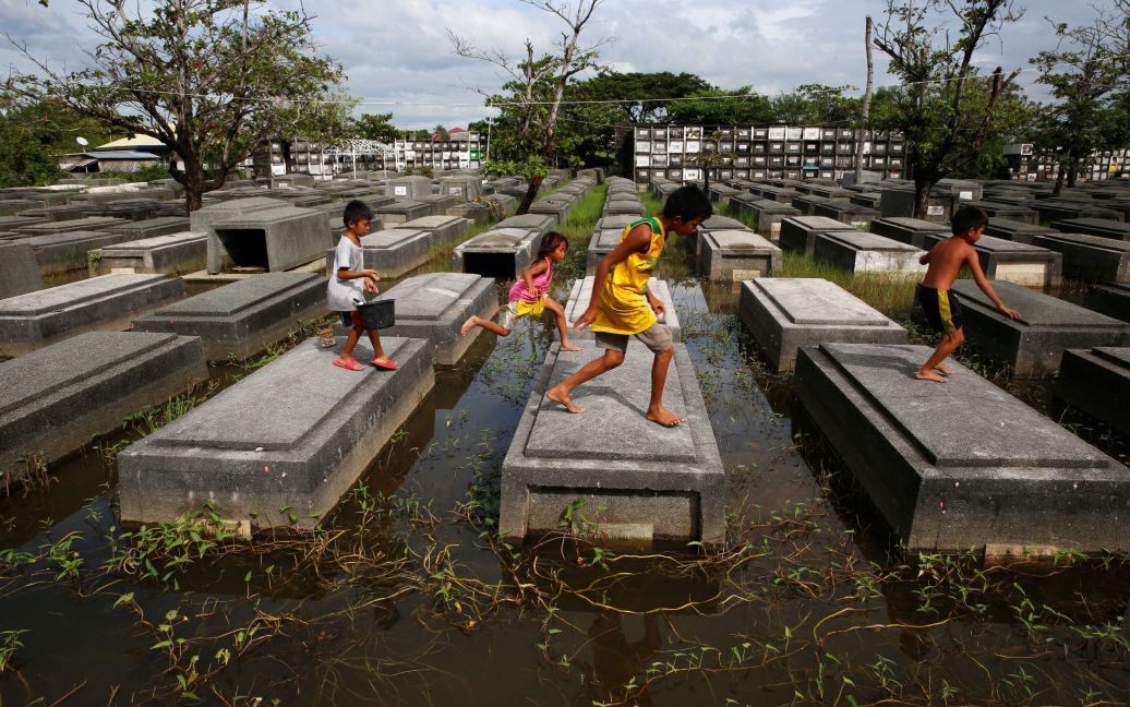 Местные жители ходят по могилам на затопленном кладбище в городе Пампанья на севере Филиппин. / © Reuters