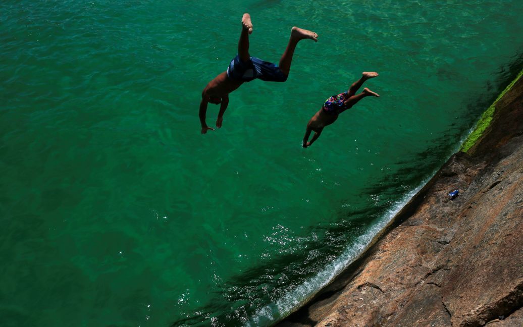 Мужчины прыгают в море на пляже Лемме в Рио-де-Жанейро, Бразилия. / © Reuters