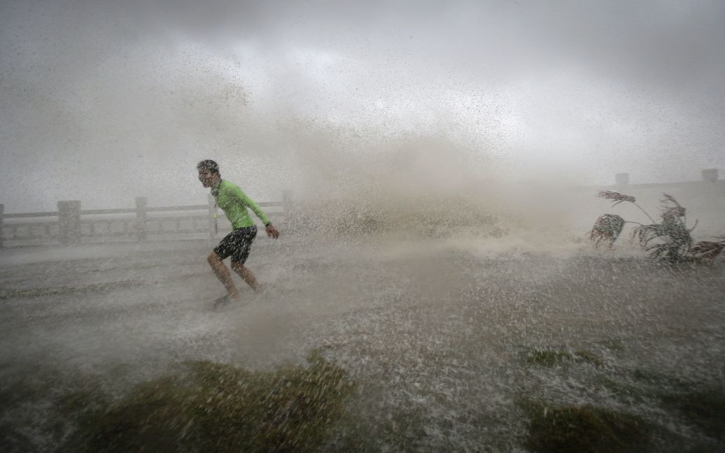 Человек убегает от волны на пляже во время тайфуна Сарика в провинции Хайнань, Китай. / © Reuters