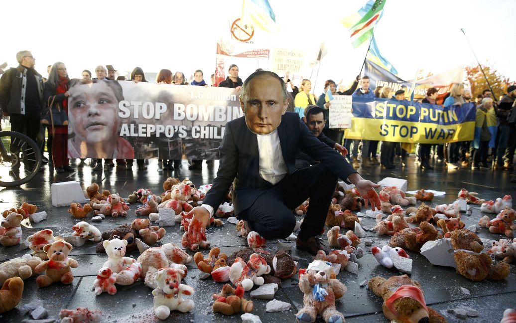 Протестующий в маске с изображением президента России Владимира Путина принимает участие в демонстрации перед Рейхсканцелярией во время его визита в Берлин, Германия. / © Reuters