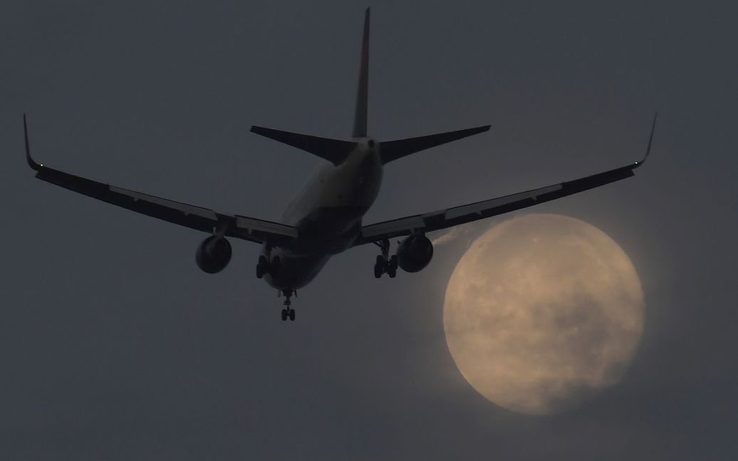 Пассажирский самолет заходит на посадку в аэропорту Хитроу на фоне Суперлуния, Лондон, Великобритания. / © Reuters