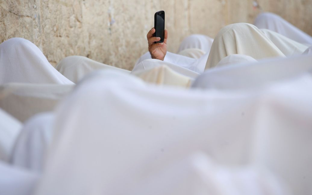 Иудей использует свой мобильный телефон, чтобы записать на видео поклонение у Стены плача в Старом городе Иерусалима во время еврейского праздника Суккот. / © Reuters