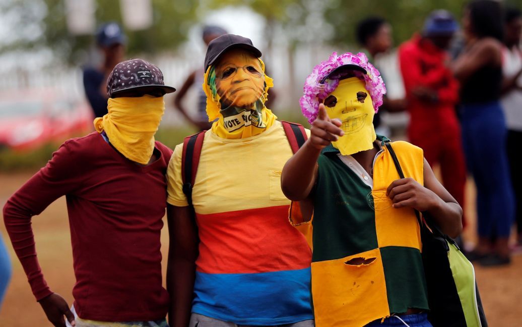 Протестувальники у масках жестикулюють у бік фотографа під час акції протесту з вимогою безкоштовної вищої освіти у Північно-Західному університеті у місті Вандербійлпарк, Південна Африка. / © Reuters