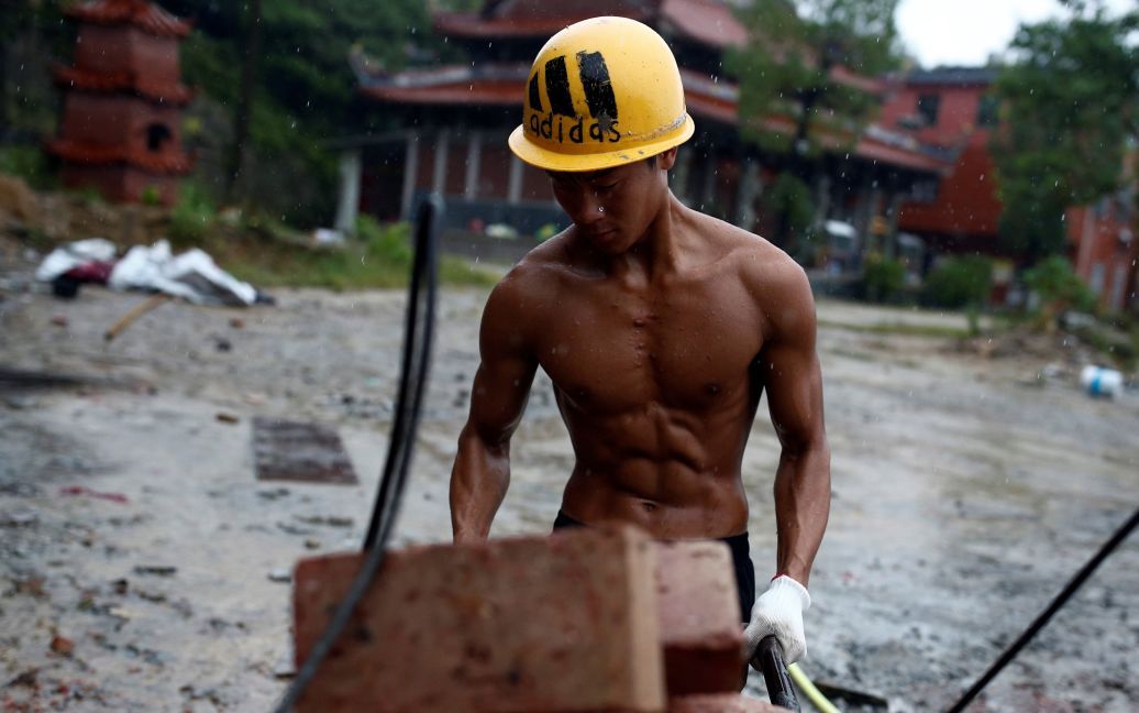 Робітник-бодібілдер Ши Шенвей тягне тачку на місці будівництва буддійського храму в селі Хуаншань, недалеко від Цюаньчжоу, провінція Фуцзянь, Китай. / © Reuters