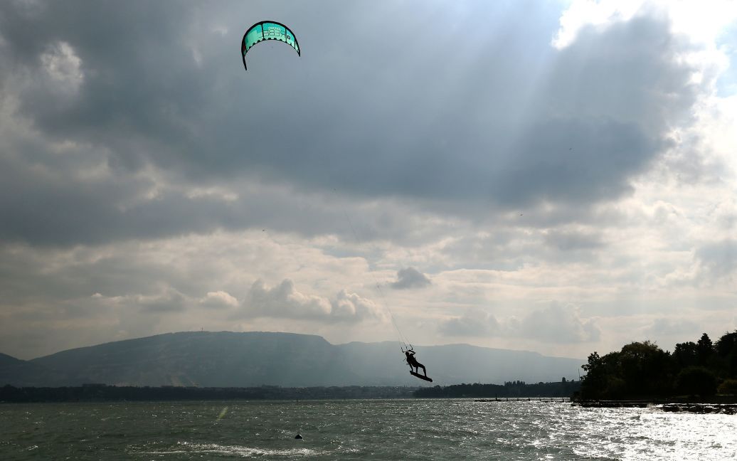 Человек занимается кайтсерфингом в сильный ветреный день на озере Леман в Женеве, Швейцария. / © Reuters