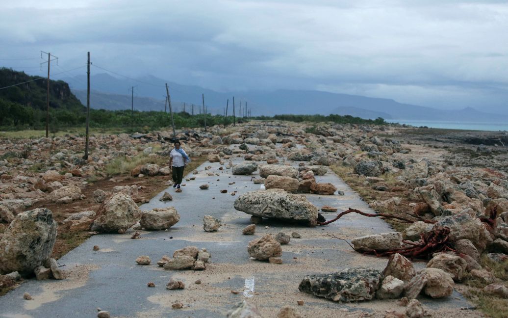 Женщина идет по шоссе, набитом камнями после прохождения урагана Мэтью на побережье провинции Гуантанамо, Куба. / © Reuters