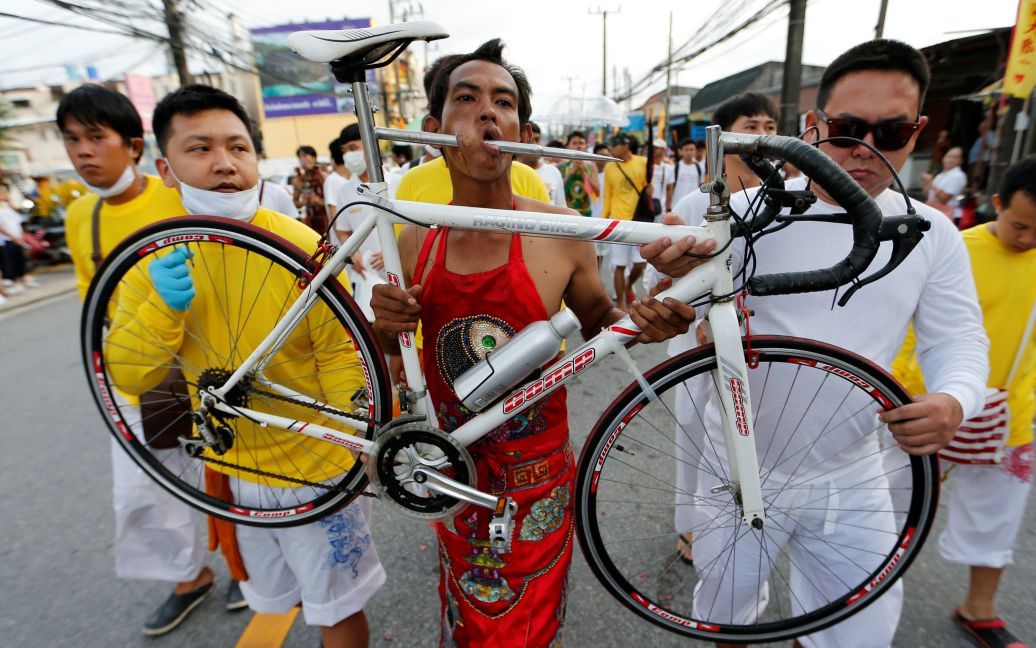 Член китайской общины в Таиланде идет с проколотым велосипедом ртом во время ежегодного вегетарианского фестиваля в Пхукете, Таиланд. / © Reuters