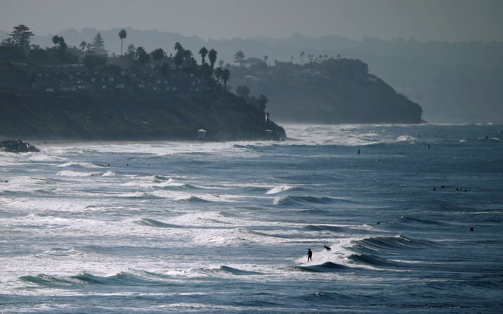 Люди наслаждаются пляжем и волнами в осенний день вдоль побережья в Карлсбаде, штат Калифорния, США. / © Reuters