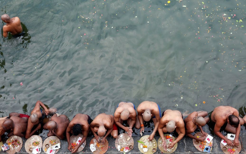 Индуистские преданные молятся после погружения в священном пруду, чтобы почтить души своих умерших предков в благоприятный день Махалайя в Мумбаи, Индия. / © Reuters