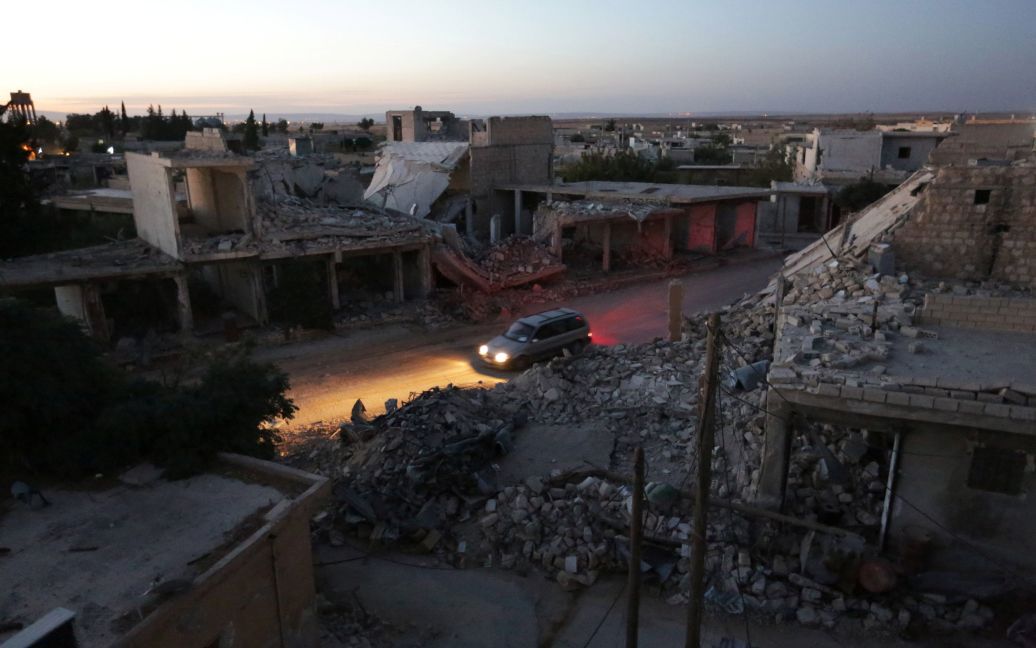 Машина проезжает мимо разрушенных зданий в северной части контролируемого сирийскими повстанцами городе Аль-Раи в провинции Алеппо, Сирия. / © Reuters