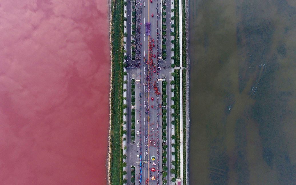 Соленое озеро, отделенное дорогой, окрашенное в разные цвета через водоросли, в городе Юнчен, Китай. / © Reuters