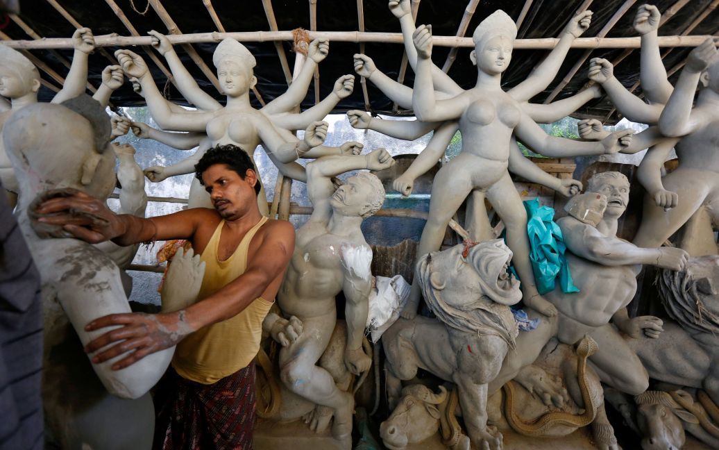 Ремесленник работает над идолом индусской богини Дурги накануне праздника в ее честь в Калькутте, Индия. / © Reuters
