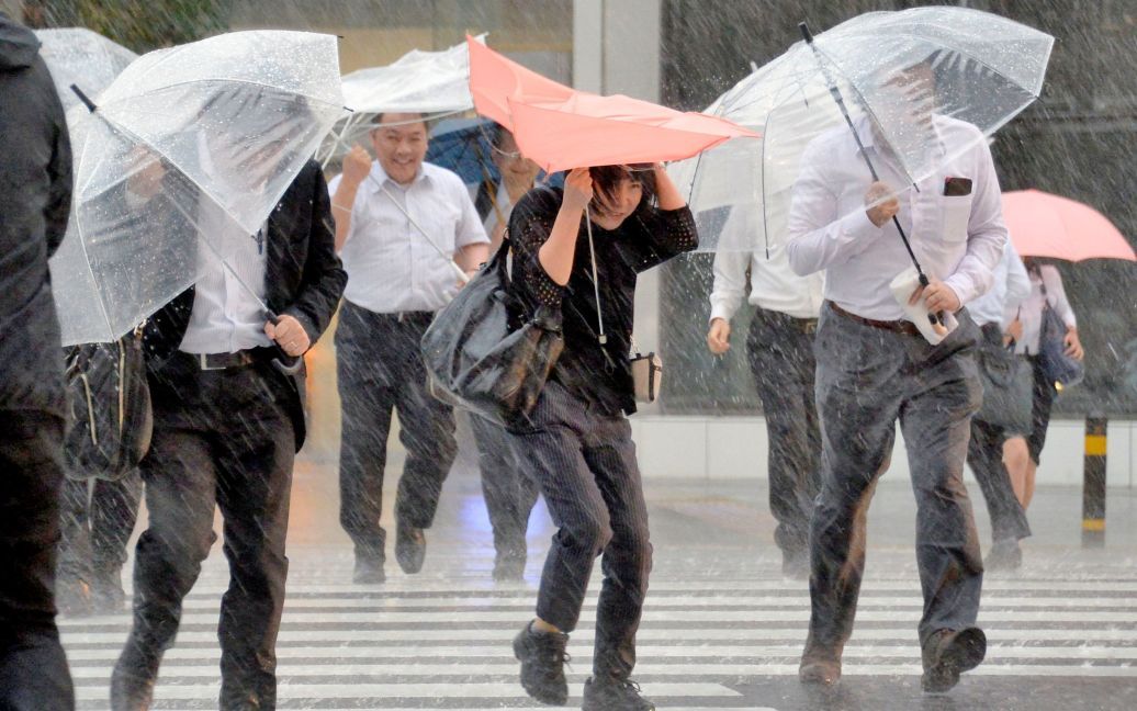 Пешеходы с зонтами борются против сильного ветра и сильных дождей, вызванных тайфуном Малакаси в Нагое, центральная Япония. / © Reuters