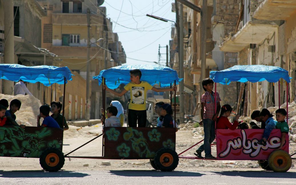 Дети катаются на тележках на третий день праздника Ид аль-Адха в контролируемом повстанцами городе Идлиб, Сирия. / © Reuters