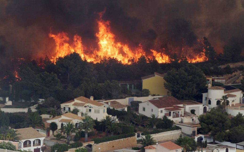 Пламя лесного пожара поглощает склон холма рядом с домами недалеко от Аликанте, Испания. / © Reuters