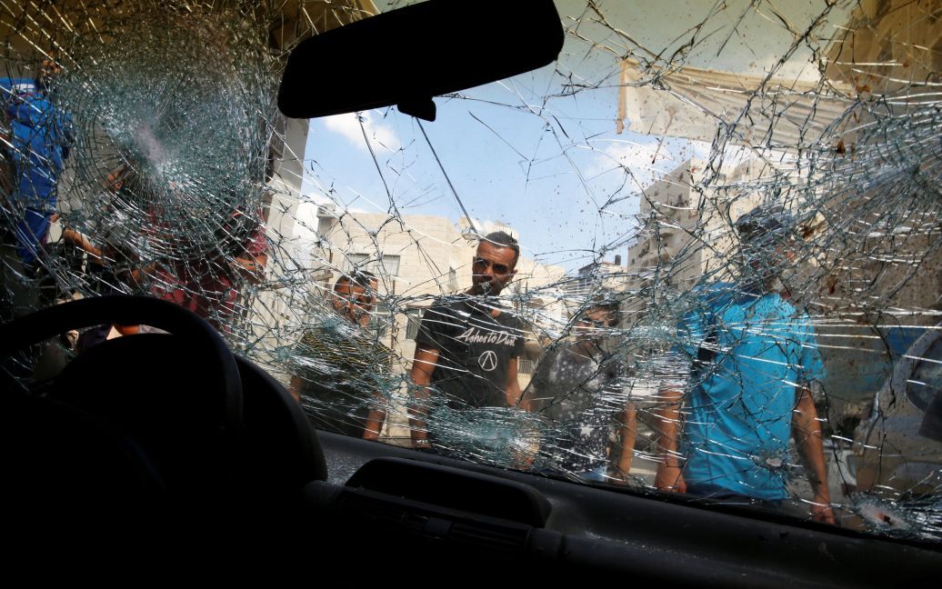 Палестинці оточують машину палестинця Мустафи Німера, який, за словами ізраїльської поліції, спробував протаранити поліцейських і був застрелений у відповідь. Це відбулося у таборі для біженців Шуафат поблизу Єрусалима. / © Reuters