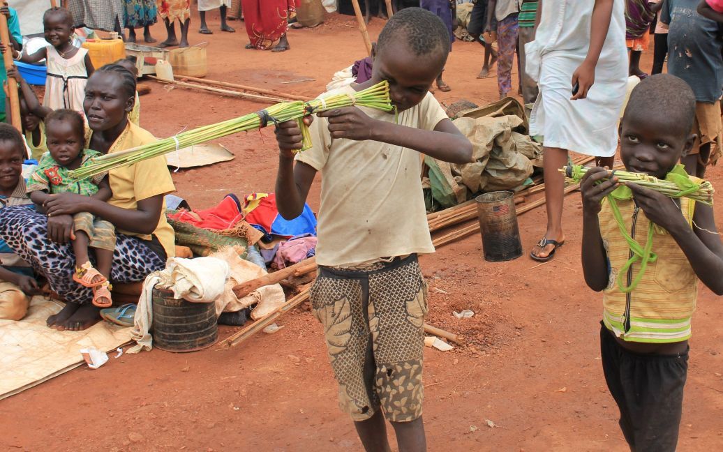 10-летний мальчик и его друг играют с игрушечными ружьями, сделанными из длинных камышей в лагере для беженцев под защитой миротворцев ООН в Вау, Южный Судан. / © Reuters