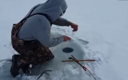 Друг снял на видео, как шокированный рыбак достал из проруби неожиданную добычу