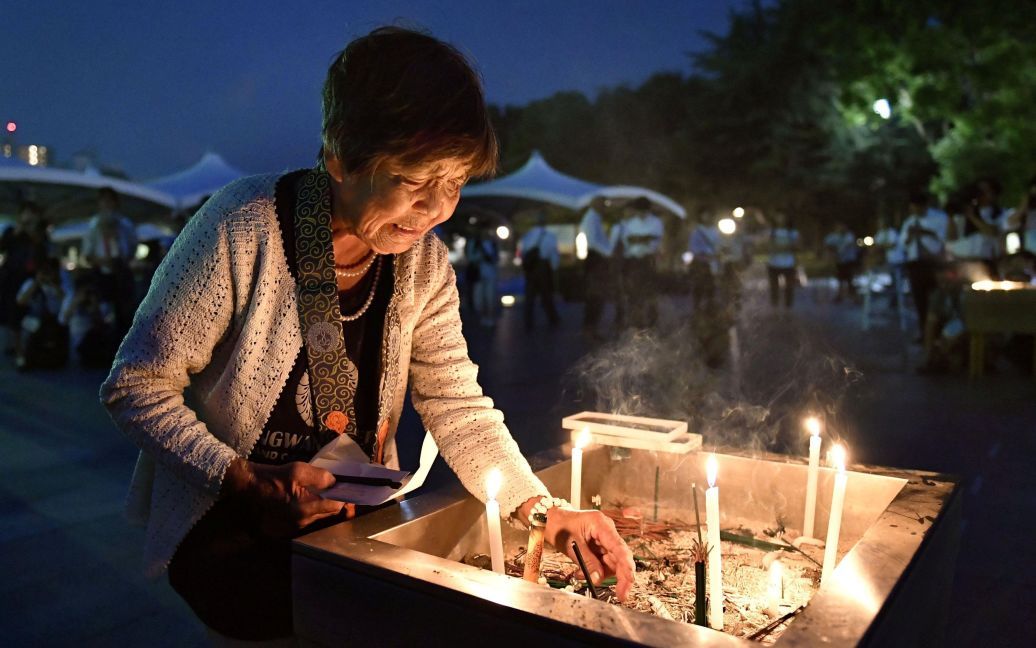 Женщина зажигает свечи, почтив память погибших в Хиросиме / © Reuters