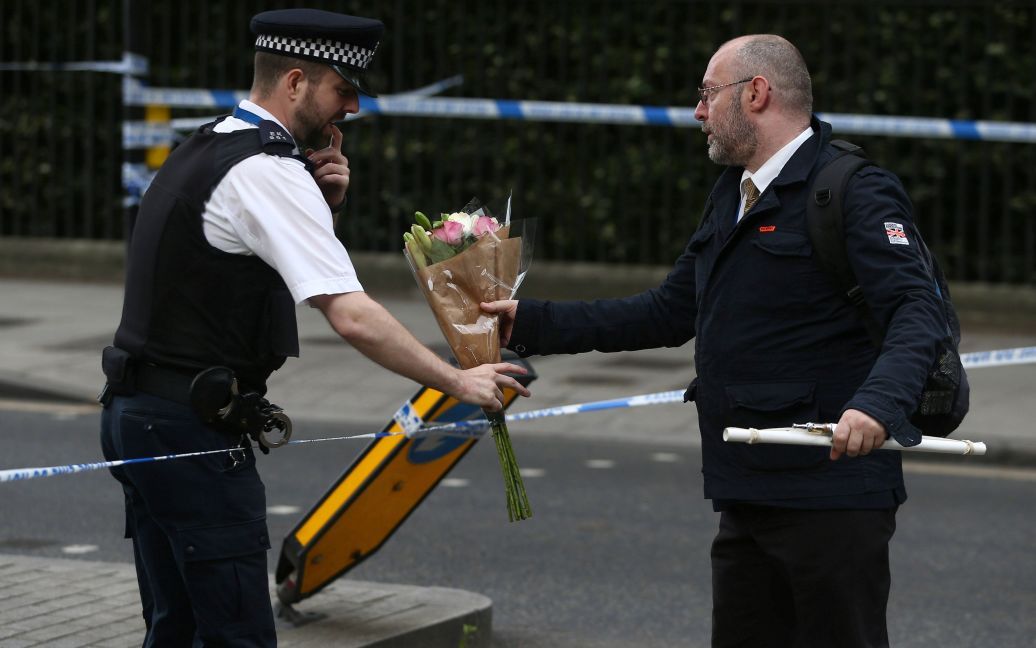 Полицейский несет цветы на место атаки на Рассел-Сквер / © Reuters