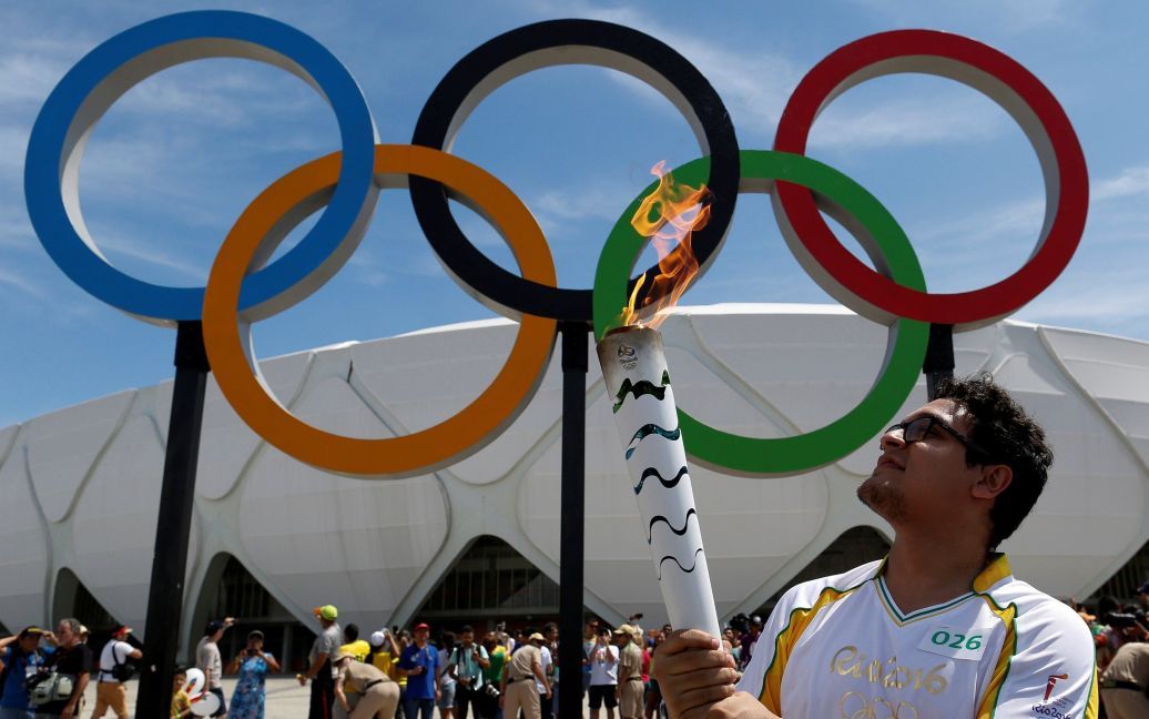 19 червня. Бразильський дизайнер Глаубер Пенха з Олімпійським вогнем перед стадіоном Arena da Amazonia stadium у місті Манаус. / © Reuters