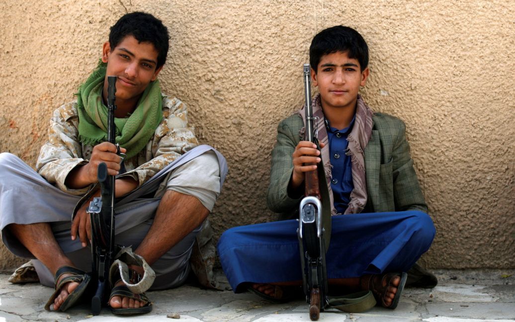Молодые боевики-хуситы сидят на обочине дороги, охраняя дорогу рядом с офисом ООН в столице Йемена Сане, где дети протестовали против удаления саудовской коалиции из черного списка нарушителей прав ребенка. / © Reuters