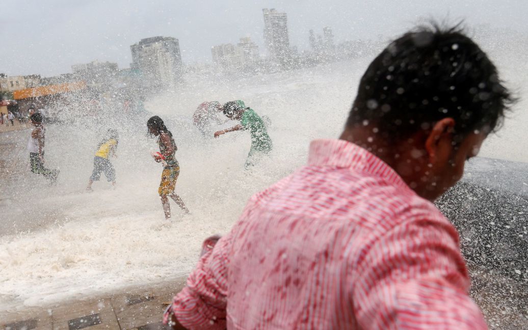 Люди намокают от большой волны во время прилива на берегу моря в Мумбаи, Индия. / © Reuters