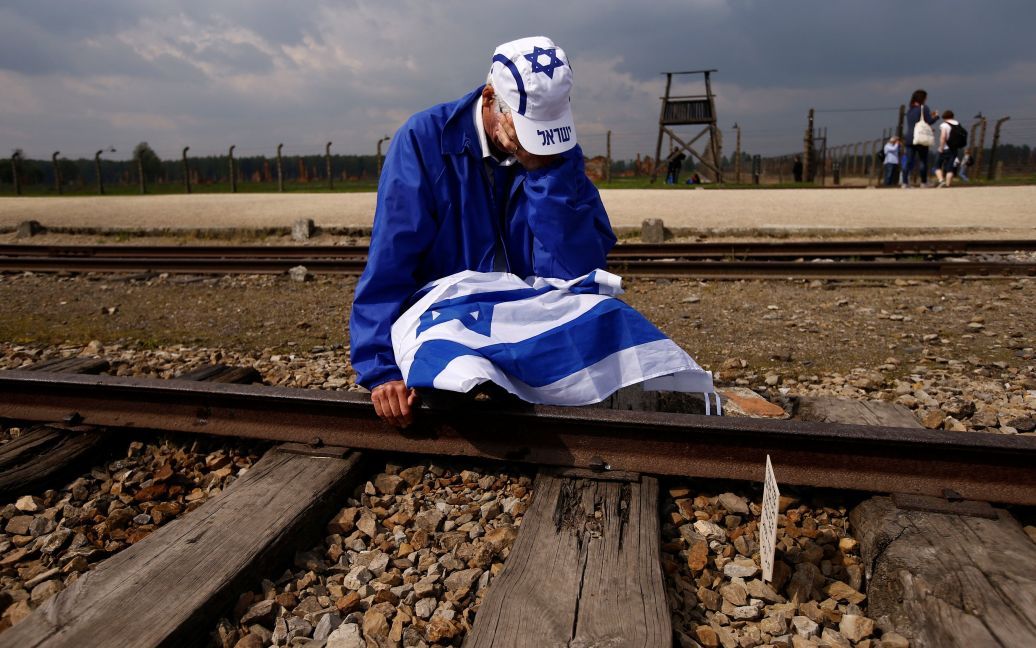 Мужчина плачет, сидя на железнодорожных путях в бывшем нацистском лагере смерти Освенцим-Биркенау, где тысячи людей со всего мира собрались на ежегодный "Марш живых", чтобы почтить память жертв Холокоста. / © Reuters