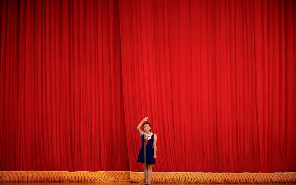 Девочка отдает честь посетителям концерта в детском дворце в центре Пхеньяна, Северная Корея. Местные школьники выступили перед делегациями иностранных журналистов и туристов накануне седьмого съезда Трудовой партии Кореи. / © Reuters