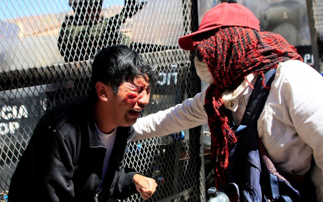 Демонстрант допомагає своєму травмованому товаришеві під час акції протесту людей з обмеженими фізичними можливостями, які вимагають від  уряду збільшити щомісячні виплати по інвалідності, в Ла-Пас, Болівія. / © Reuters