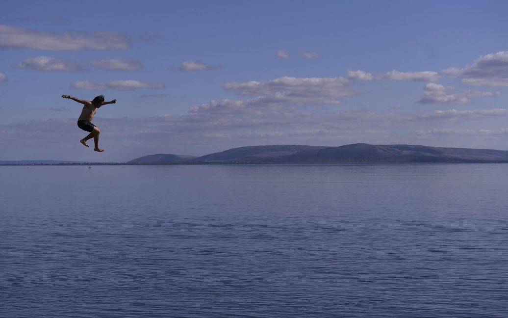 Молода людина стрибає в воду на пляжі Солтхілл в Голуей, Ірландія. / © Reuters